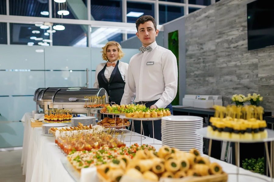 caters of cater4ingg company standing behind a buffet table at a corporate event.